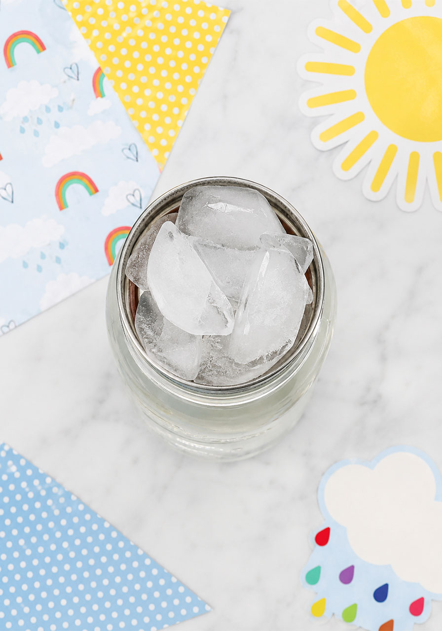 Ice cubes placed on upside-down lid for cloud in a jar science experiment