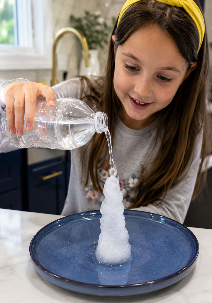Child pouring supercooled water onto an ice cube to instantly form an ice tower
