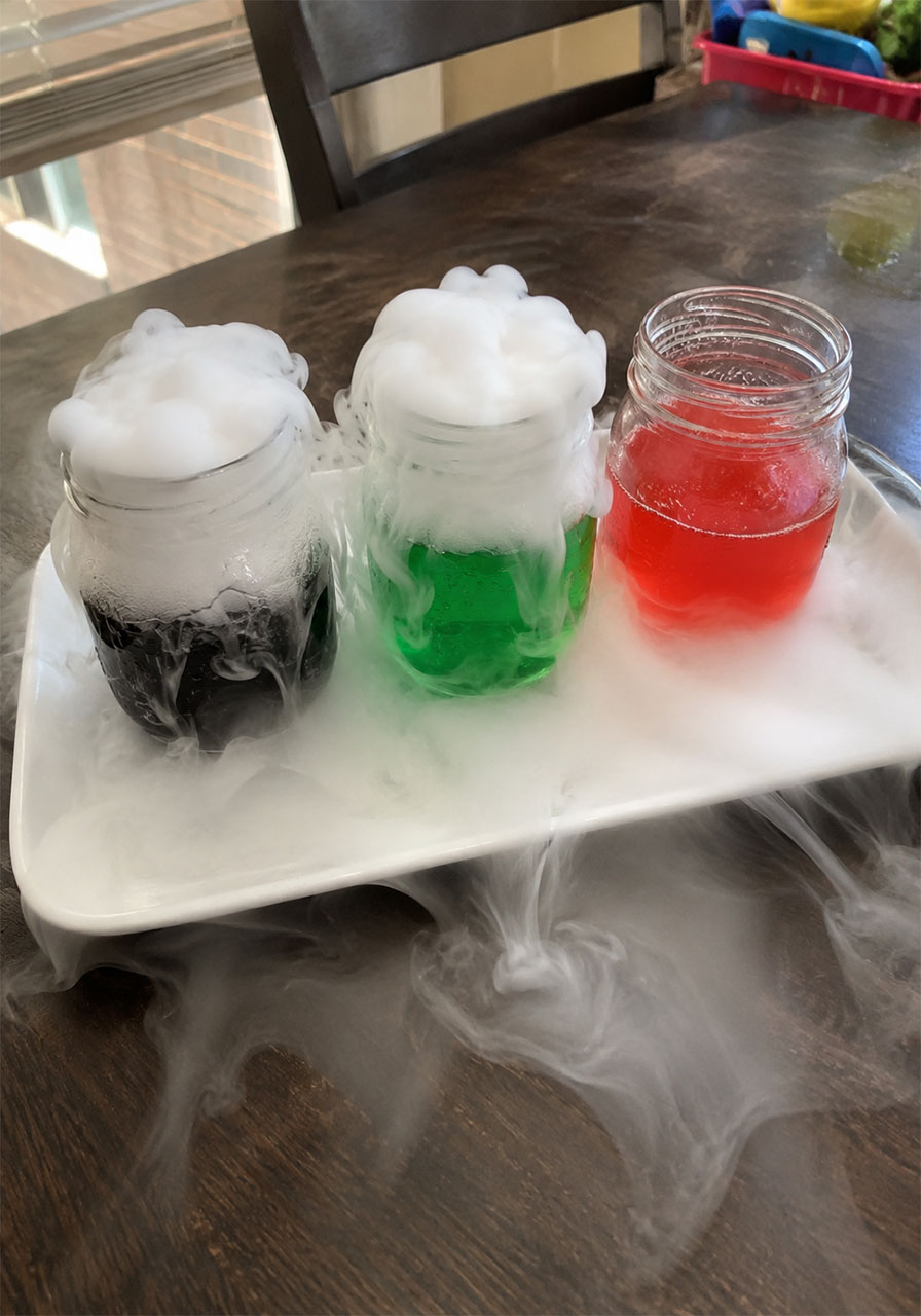 Three glowing Halloween potion jars bubbling with dry ice fog for a kids science activity