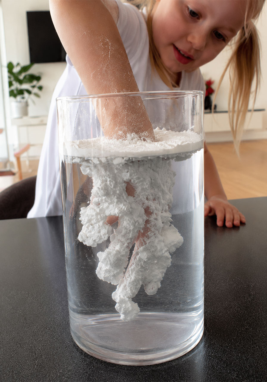 Step three of the Magic Powder Shield experiment: dipping a hand through the powder barrier into the water