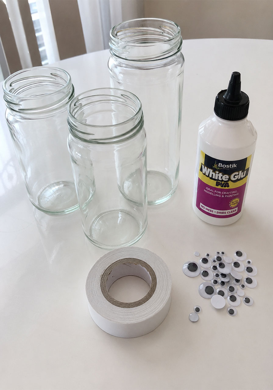 Supplies needed for mummy jar lanterns including glass jars, white tape, googly eyes, and glue
