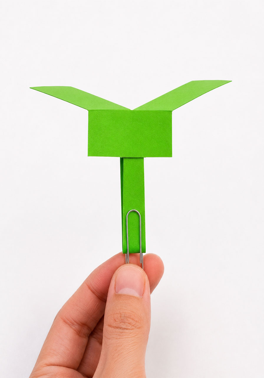 Finished paper helicopter with blades folded in opposite directions, ready to fly