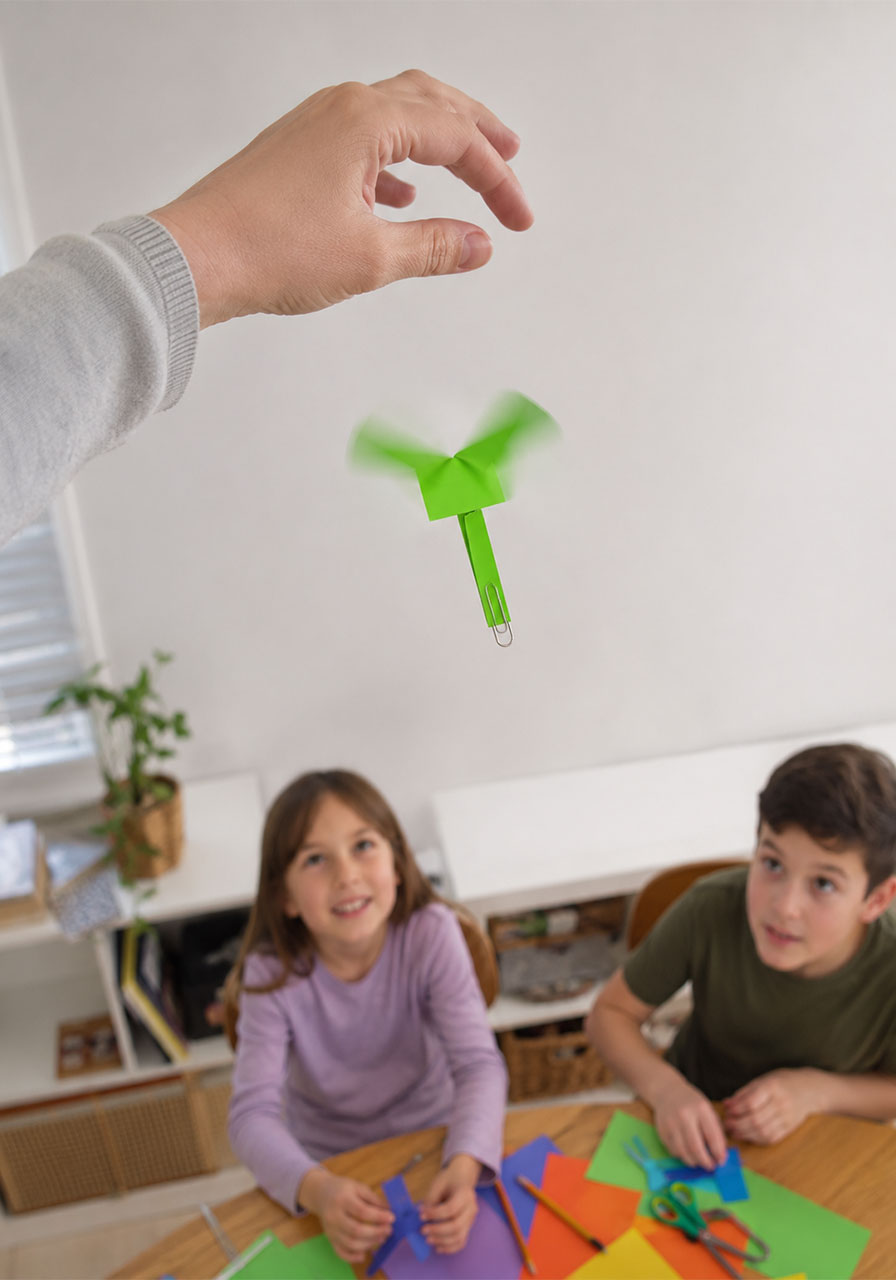 Bright green paper helicopter spinning mid-air after being dropped, an easy STEM activity for kids