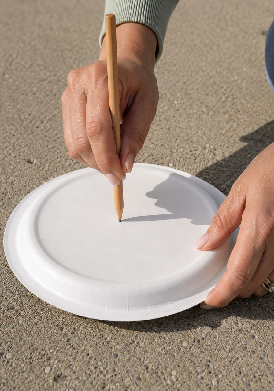 Poking a hole in the center of a paper plate to build a homemade sundial
