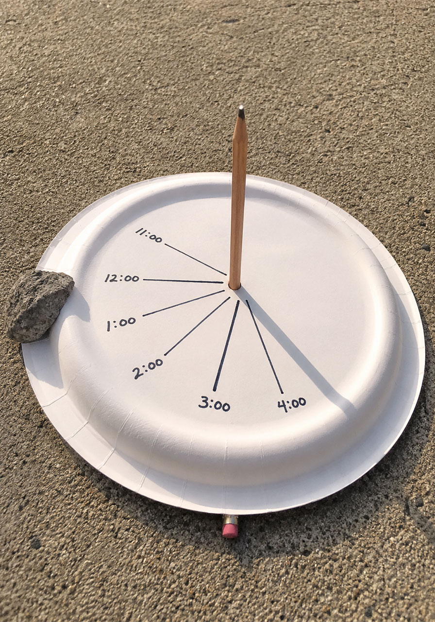 Finished paper plate sundial STEM activity showing hourly shadow lines and pencil gnomon