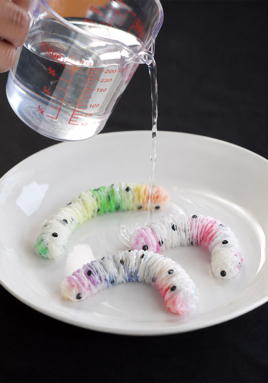 Pouring water over paper towel worms to reveal hidden rainbow colors