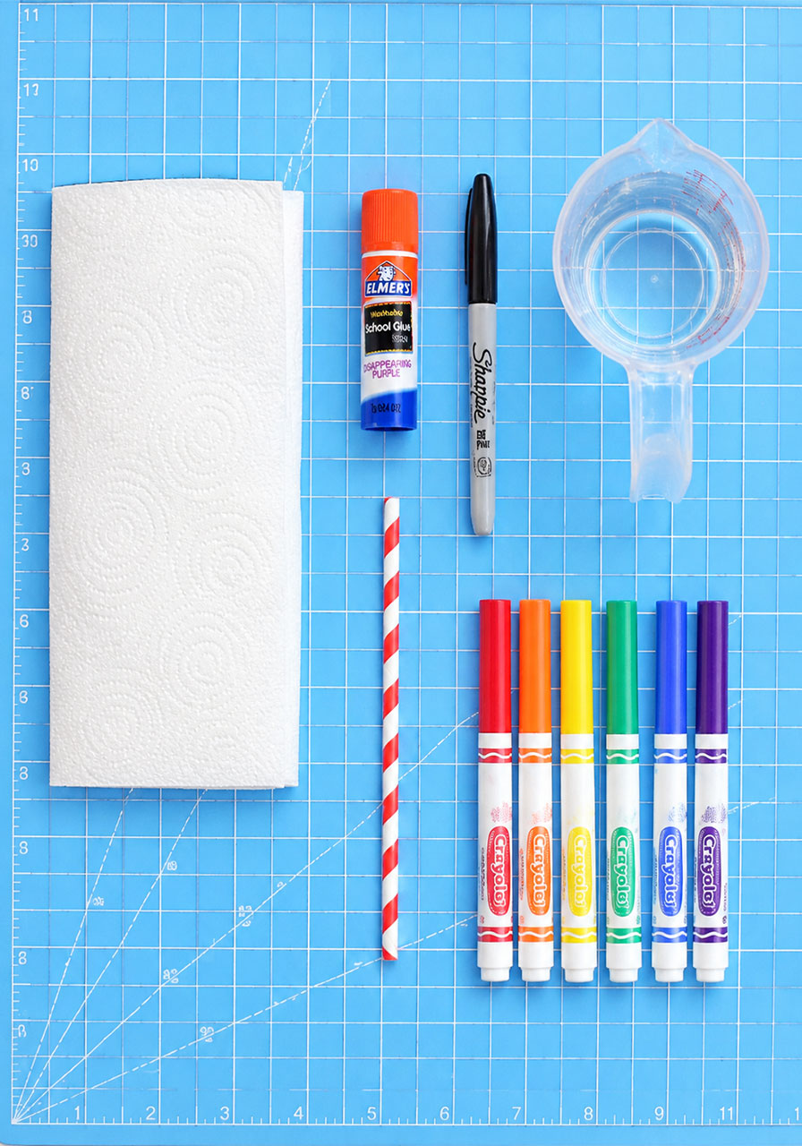 Supplies needed for the paper worm experiment including paper towel, markers, glue stick, and straw