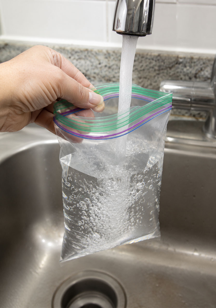 Filling a zipper bag with water for the pencil in water bag science experiment