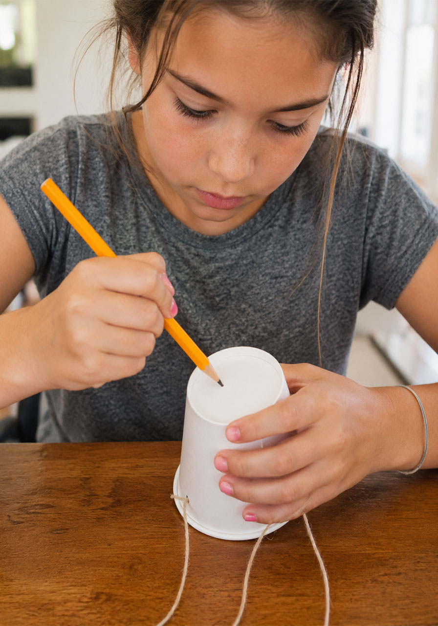 Punching a small hole in a paper cup to build a DIY pendulum for painting