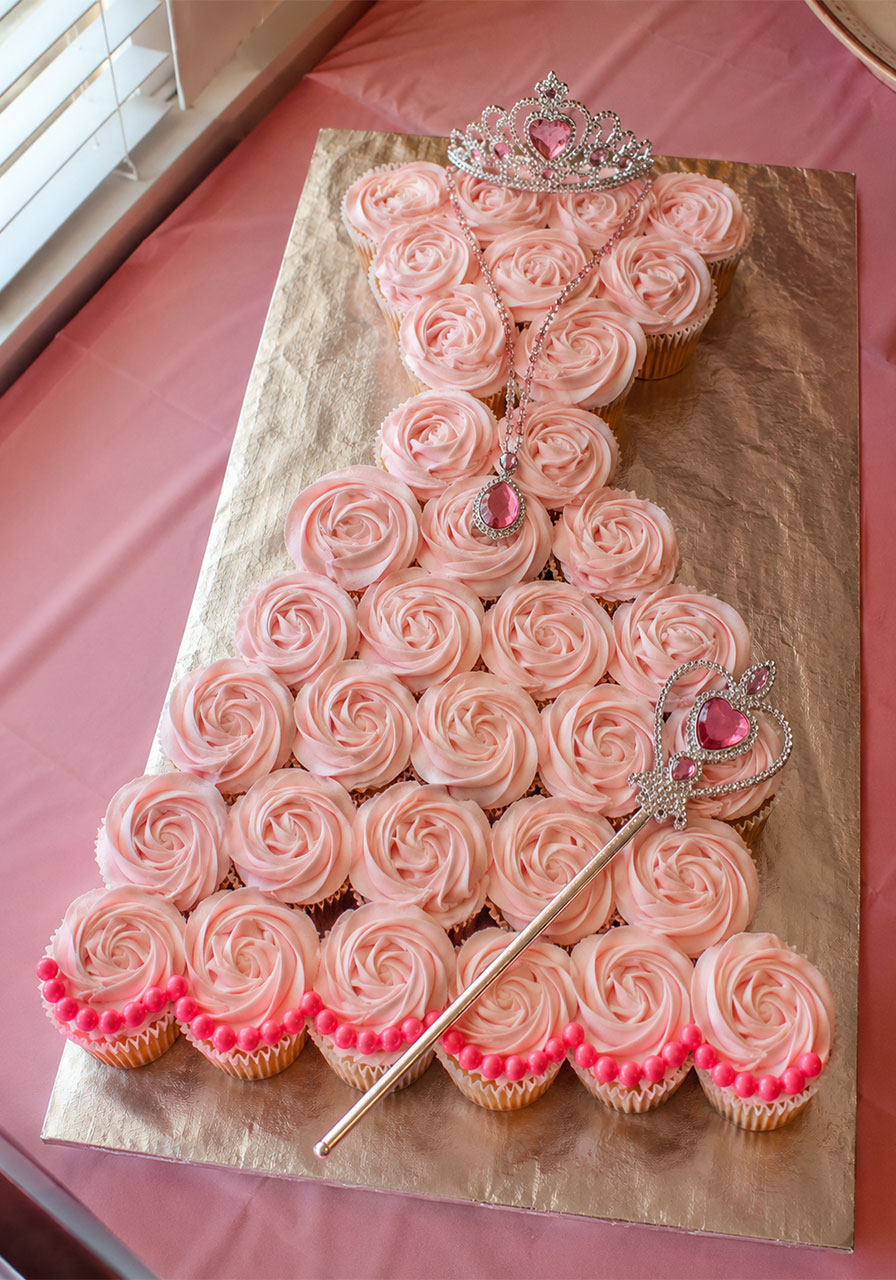 Princess dress-shaped pull-apart cupcake cake with pink rosettes and tiara for a princess birthday party