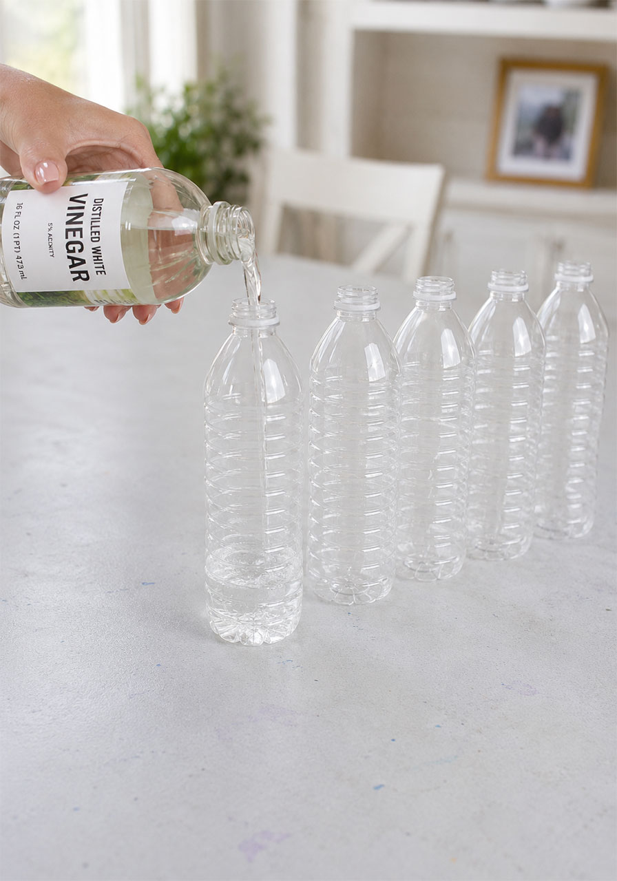 Pouring vinegar into a plastic bottle for the rainbow balloon experiment