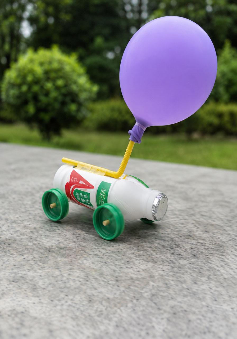 Simple recycled balloon car STEM activity zooming across a table outdoors