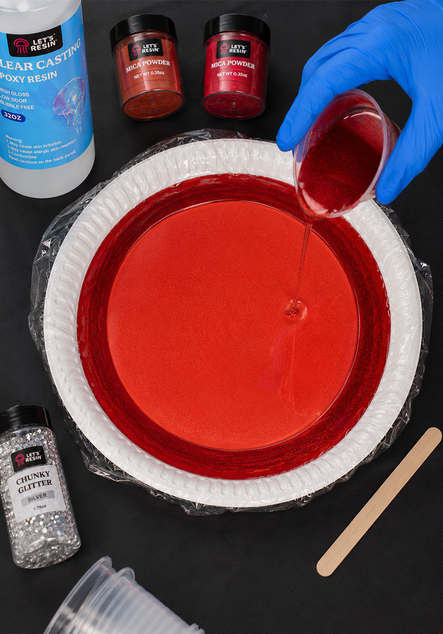Pouring layered blue resin colors onto plate for ghost craft