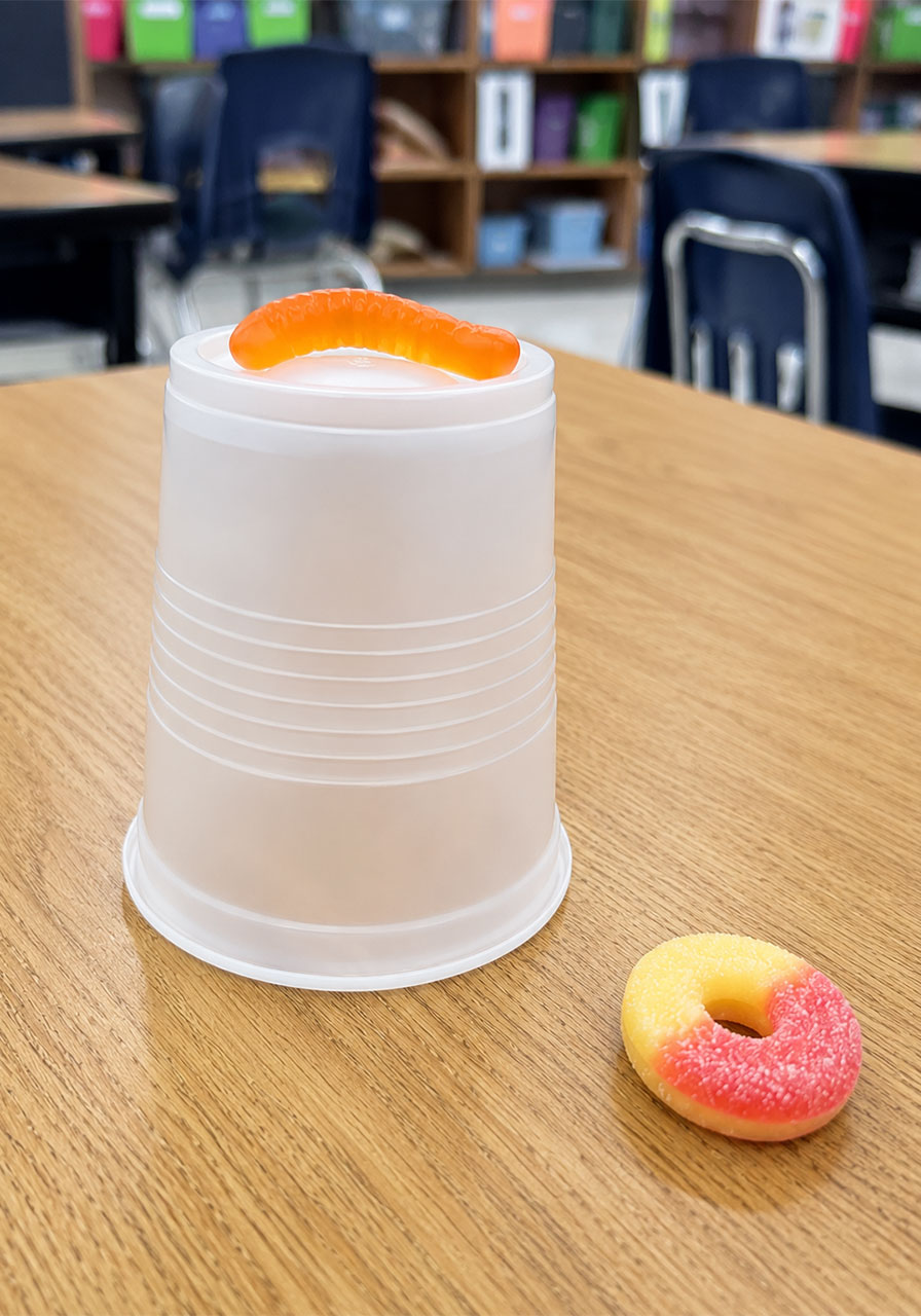 Supplies needed for the Save Fred STEM activity including cups, gummy worms, and peach rings
