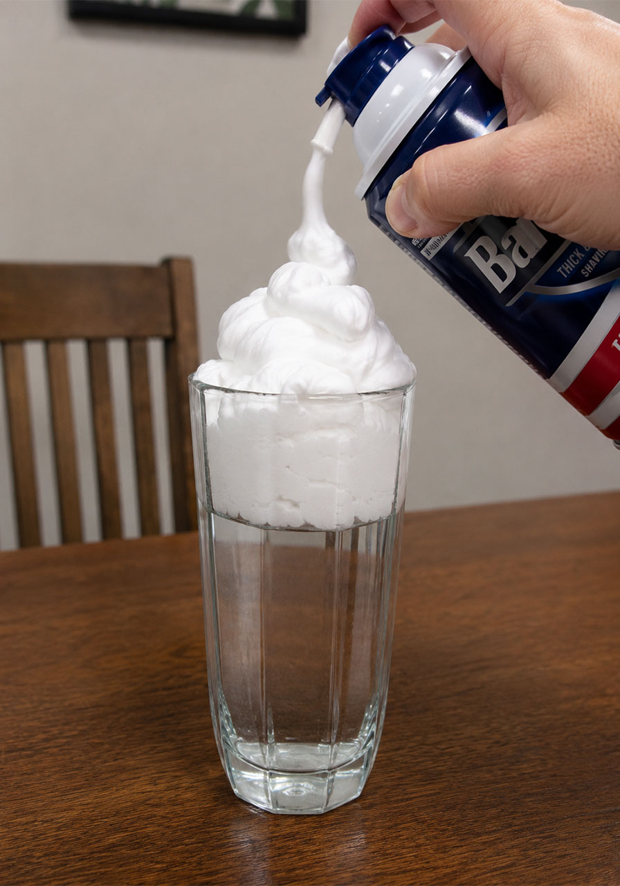 Spraying shaving cream on top of a glass of water to form a cloud for a rain cycle experiment