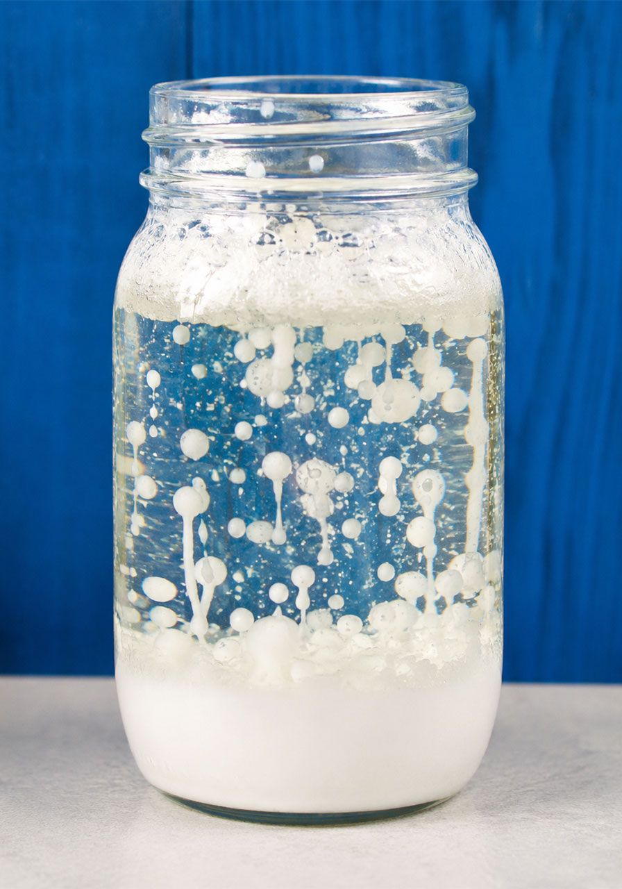 Snowstorm in a jar science experiment showing white bubbles rising through oil and water