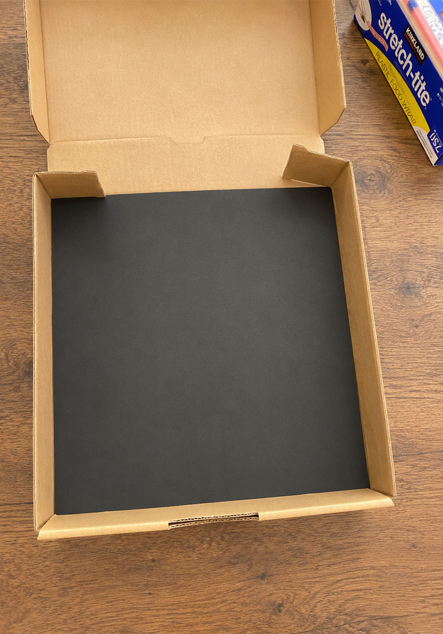 Black construction paper lining the inside of a solar oven box