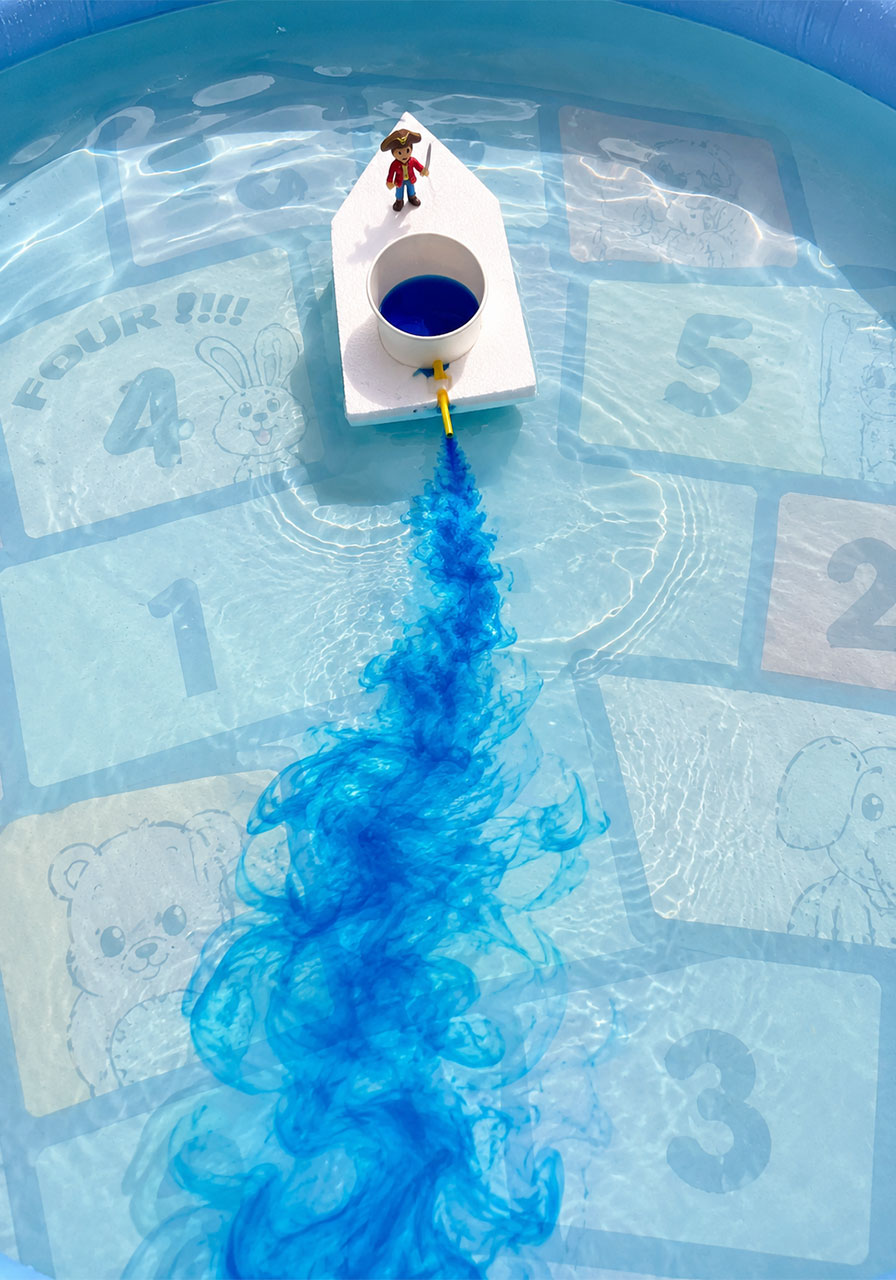 STEM boat gliding across water leaving a swirling blue color trail powered by surface tension