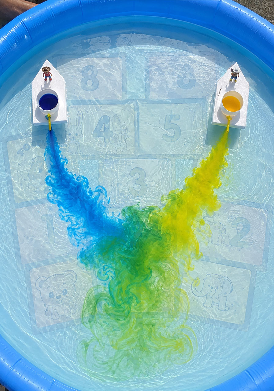 Two STEM boats racing and mixing blue and yellow color trails to teach color theory