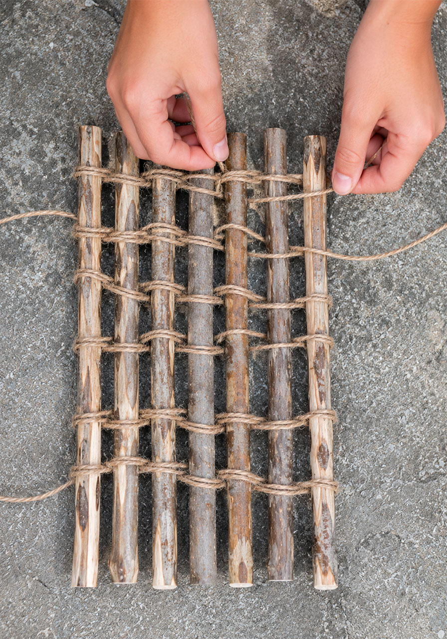 Close-up of sticks being woven together with twine to build a floating STEM raft