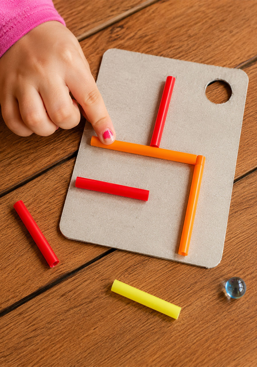 Gluing straws onto cardboard to build STEM maze path