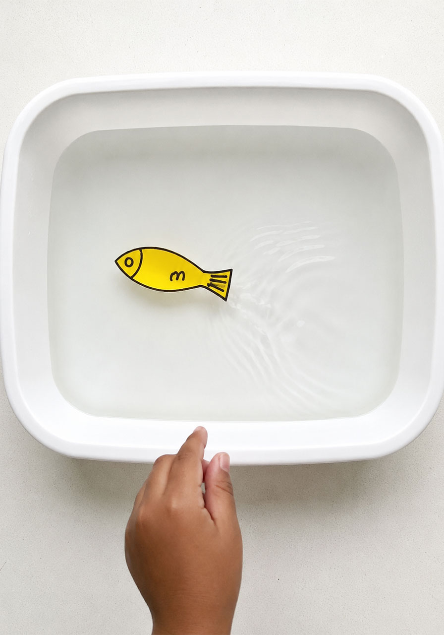 Yellow foam fish swimming across water in a fun science experiment for toddlers and kids