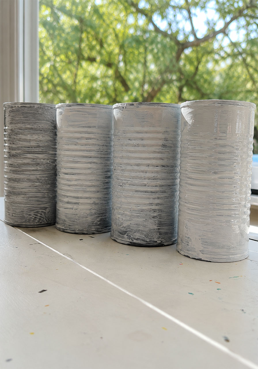 Four metal cans coated with white gesso primer before painting, step in a STEM wind chime craft