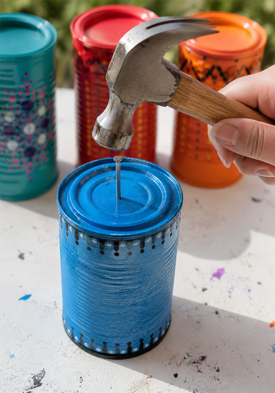 Hammering a nail through a tin can lid to create a hanging hole for a wind chime STEM project