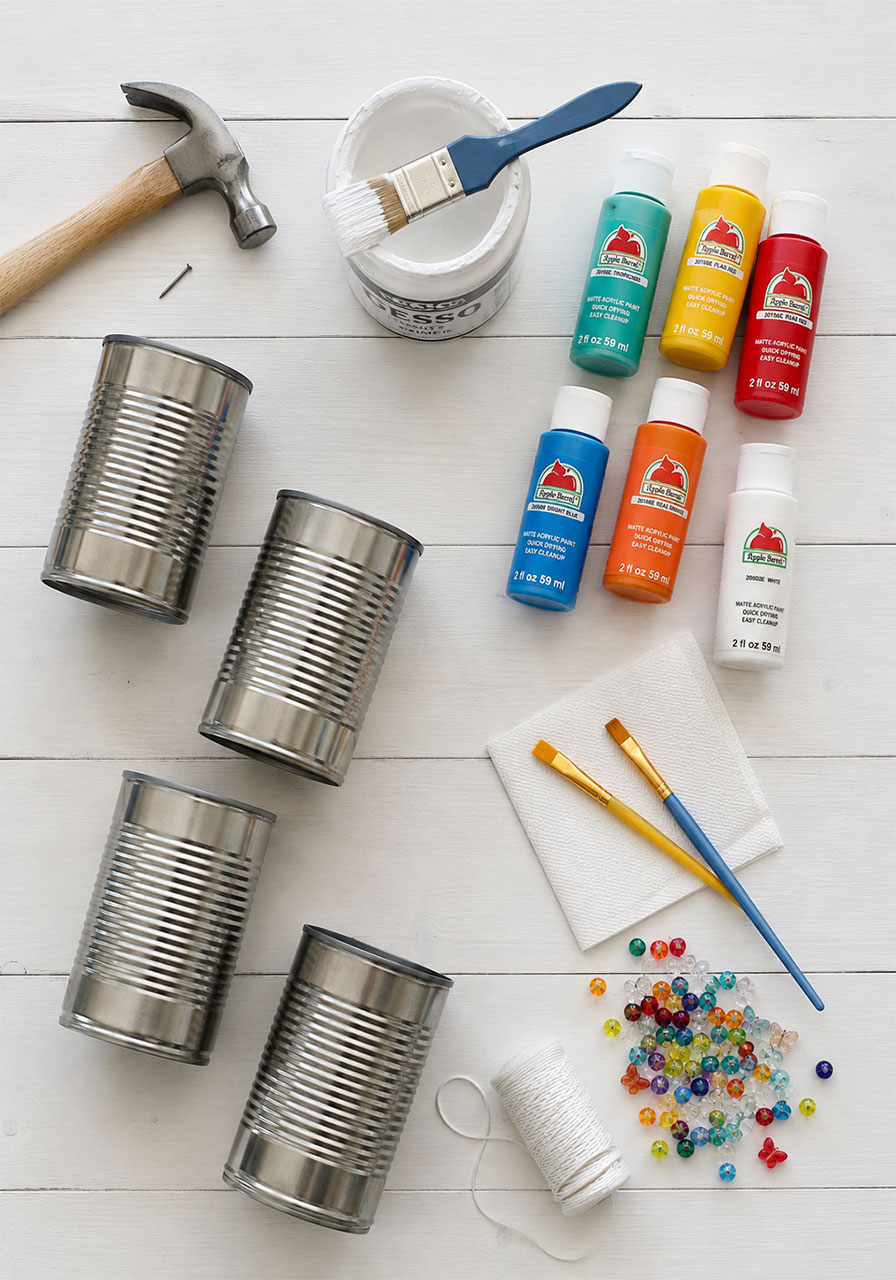 Craft supplies needed for a tin can wind chime STEM activity, including cans, paint, beads, and a hammer
