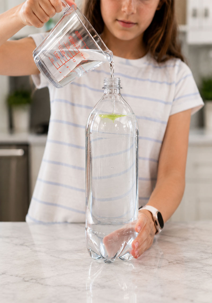 Filling a bottle with water and dish soap for the tornado in a bottle experiment