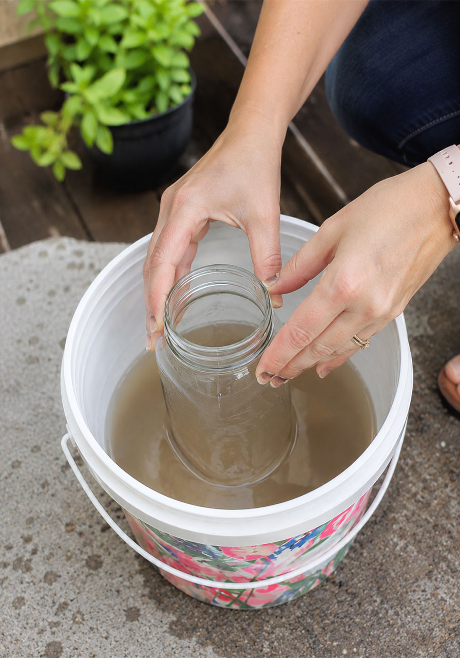 Placing a clean glass jar in the center of the bucket for a water purifier STEM activity