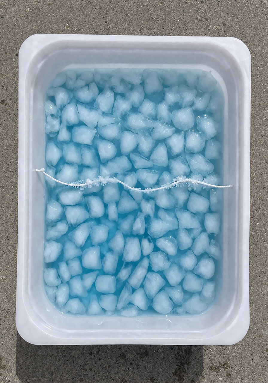 Ice cubes refreezing around string showing the science of freezing point and salt