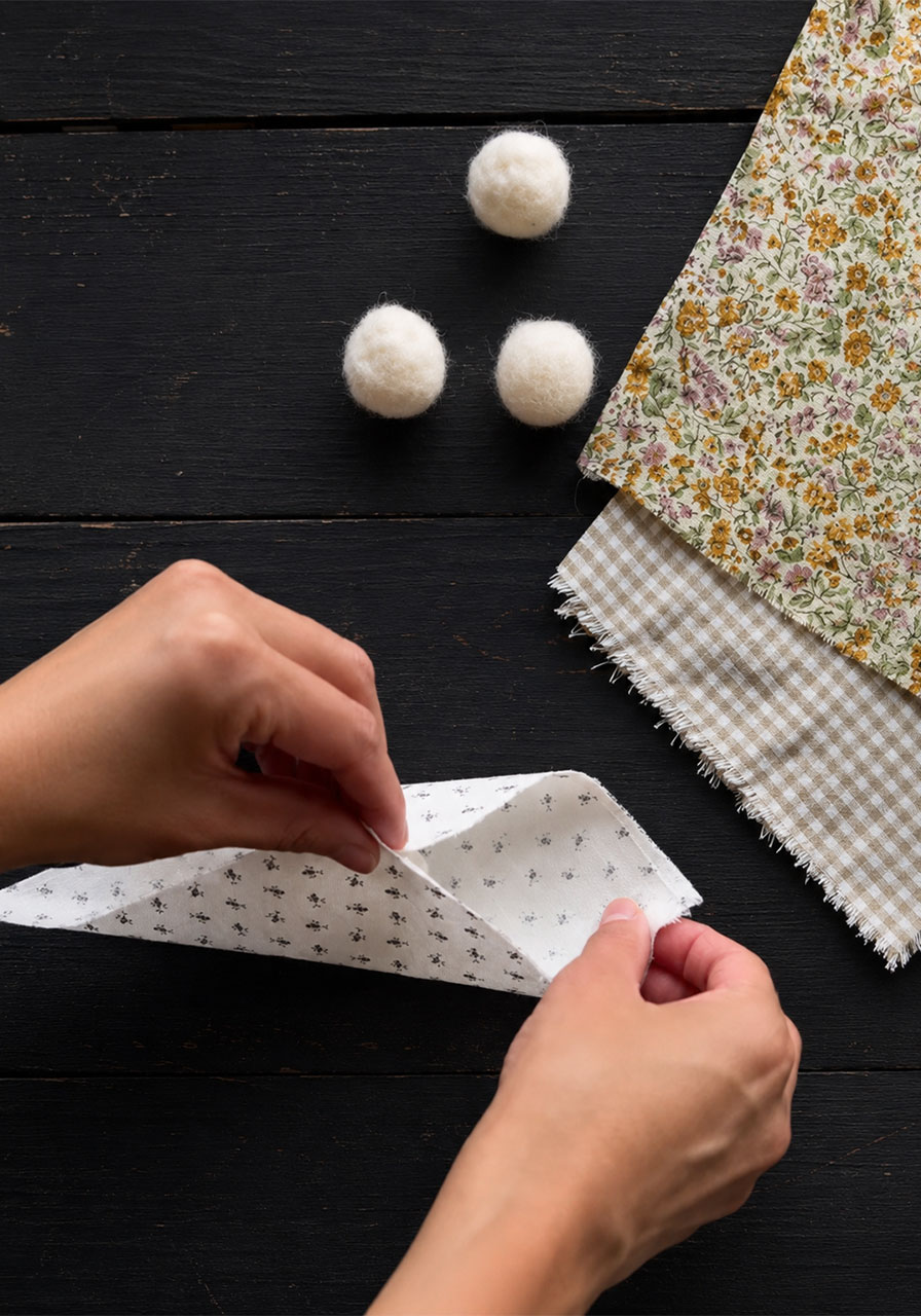 Wrapping fabric around a felted wool ball to create a ghost shape step3a